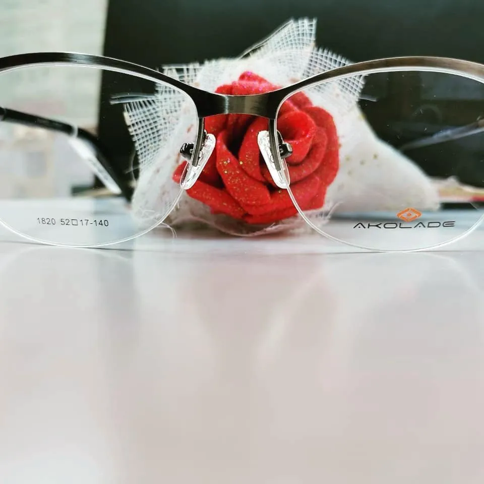 Gunmetal half-rim glasses in front of a red fabric rose