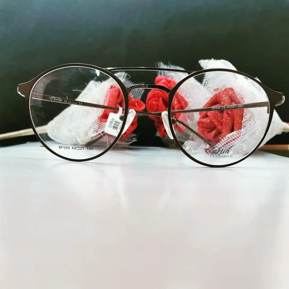 Round dark bronze double-bridge metal frame with red fabric roses behind